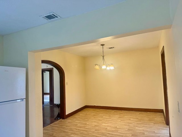 unfurnished room featuring light hardwood / wood-style flooring and a chandelier