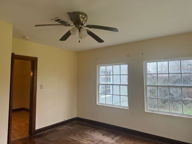 empty room featuring ceiling fan, dark hardwood / wood-style floors, and plenty of natural light