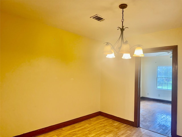 spare room featuring hardwood / wood-style flooring and a notable chandelier