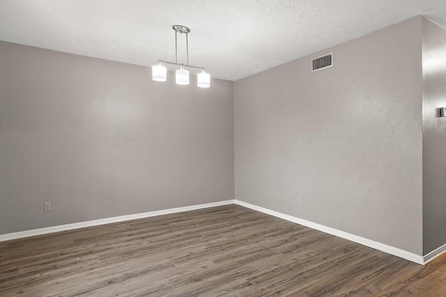 spare room with a textured ceiling and dark wood-type flooring