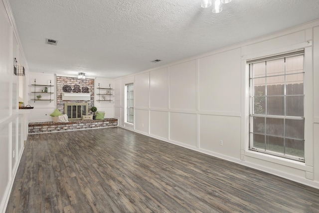 unfurnished living room with a textured ceiling, crown molding, dark hardwood / wood-style flooring, and a fireplace