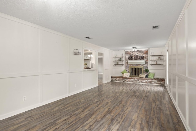 unfurnished living room with a textured ceiling, crown molding, dark hardwood / wood-style flooring, and a fireplace