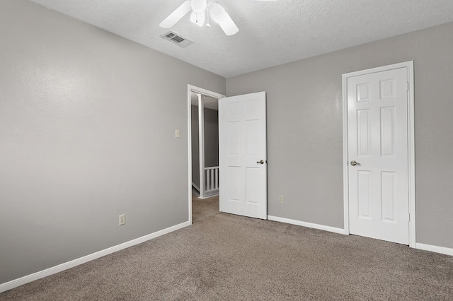 unfurnished bedroom with carpet flooring, ceiling fan, and a textured ceiling