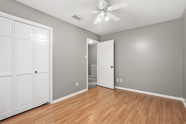 unfurnished bedroom featuring a textured ceiling, ceiling fan, light hardwood / wood-style flooring, and a closet