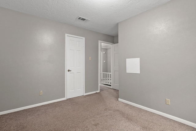 empty room featuring carpet and a textured ceiling