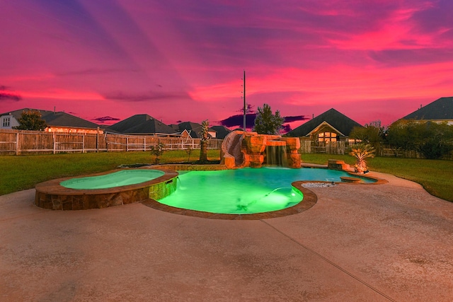 pool at dusk with an in ground hot tub and a yard