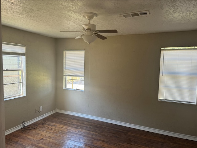 empty room featuring ceiling fan, dark wood-type flooring, and a textured ceiling