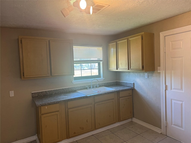 kitchen with light tile patterned floors, a textured ceiling, and sink