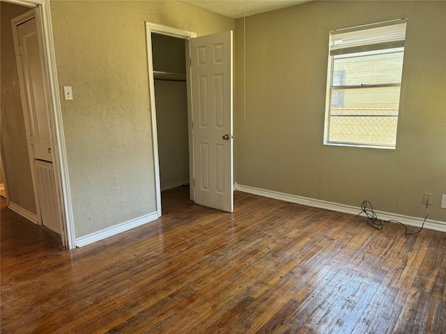 unfurnished bedroom featuring a closet and dark wood-type flooring