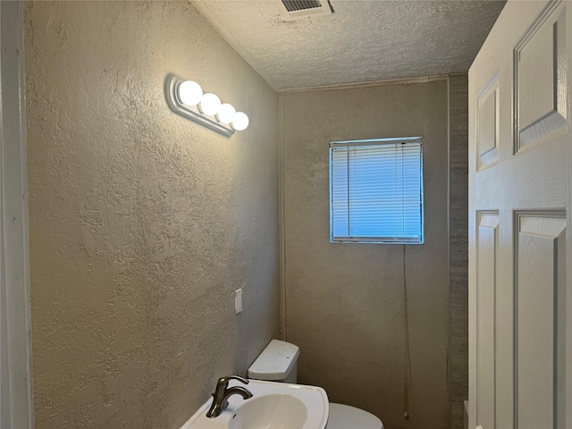 bathroom featuring sink, a textured ceiling, and toilet