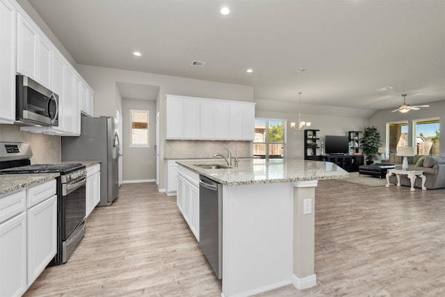 kitchen with white cabinetry, stainless steel appliances, an island with sink, pendant lighting, and ceiling fan with notable chandelier