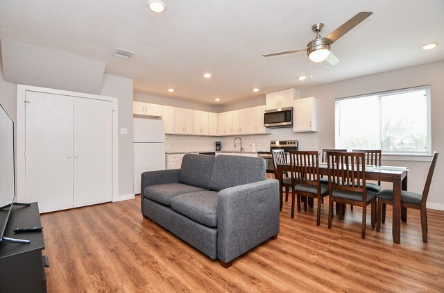 living room with ceiling fan, light hardwood / wood-style floors, and sink