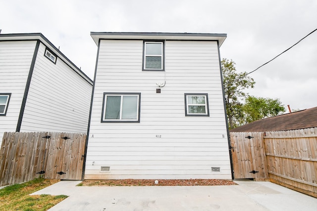 rear view of house with crawl space, a fenced backyard, and a gate