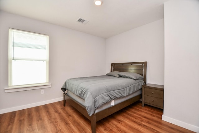 bedroom featuring visible vents, baseboards, and wood finished floors