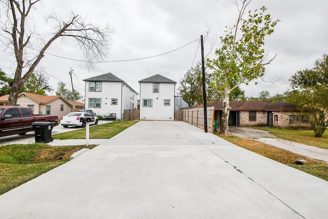 view of front facade with a residential view, fence, and concrete driveway