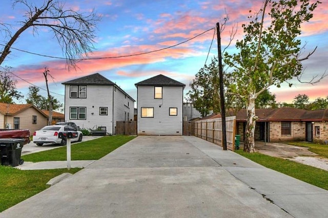 view of front of house with fence, a front lawn, and concrete driveway