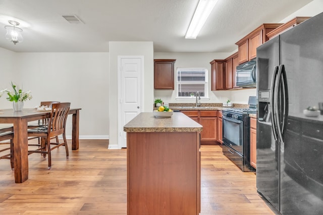 kitchen with sink, a center island, light hardwood / wood-style floors, and black appliances