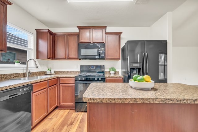 kitchen featuring sink, a center island, black appliances, and light wood-type flooring