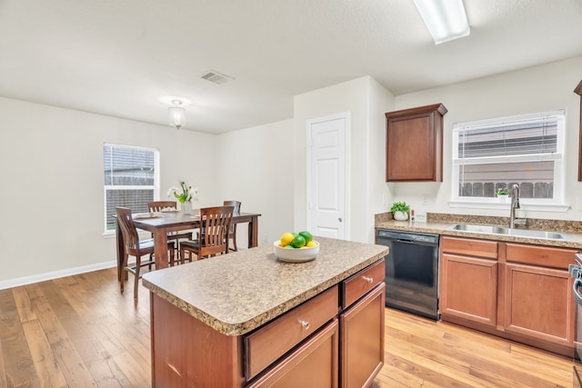 kitchen with a wealth of natural light, sink, dishwasher, a center island, and light hardwood / wood-style floors