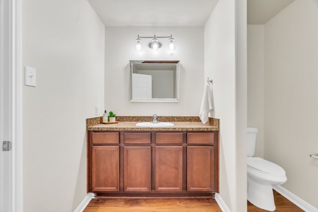 bathroom with hardwood / wood-style floors, vanity, and toilet