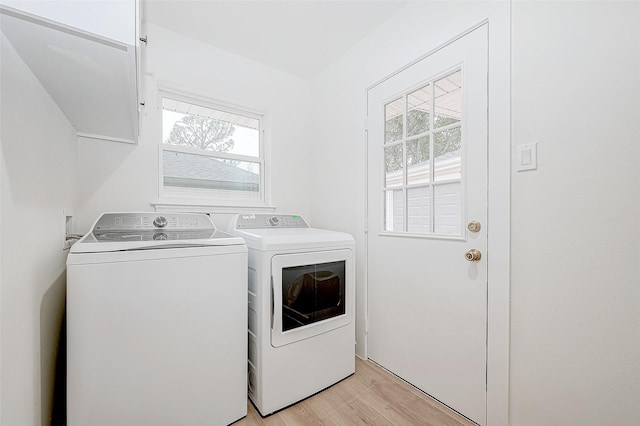 clothes washing area with washing machine and dryer and light hardwood / wood-style flooring