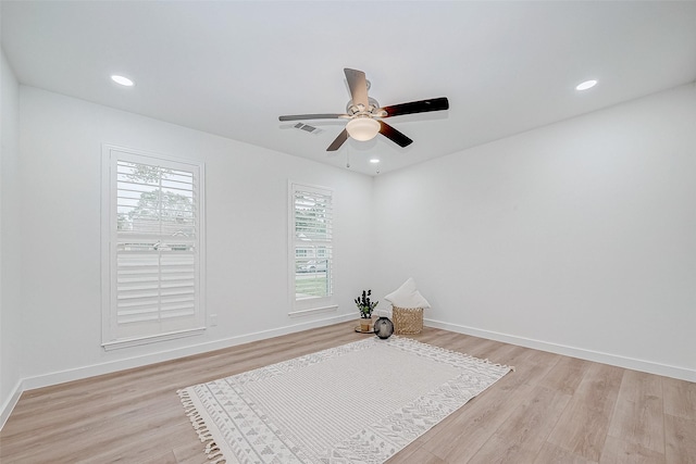 empty room with ceiling fan, plenty of natural light, and light wood-type flooring