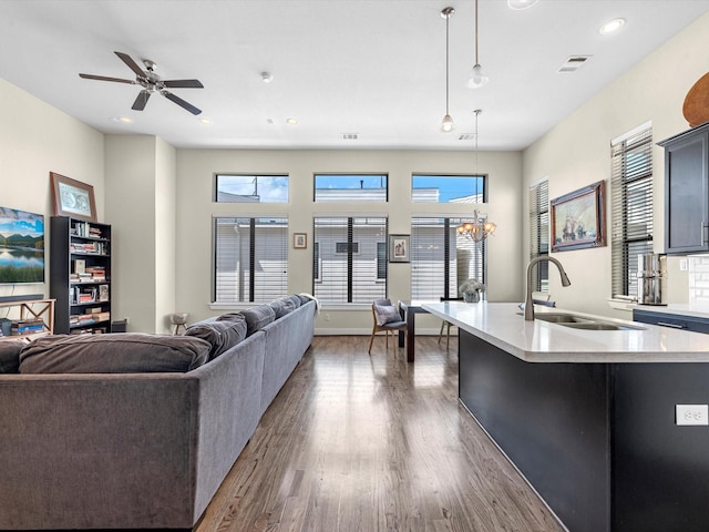 living room featuring ceiling fan with notable chandelier, dark hardwood / wood-style floors, and sink