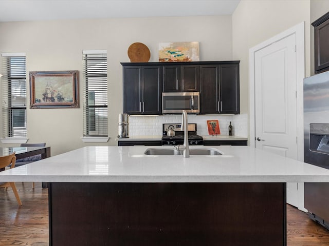 kitchen featuring backsplash, a kitchen island with sink, sink, a healthy amount of sunlight, and stainless steel appliances