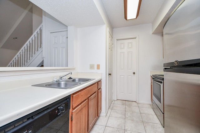 kitchen featuring light tile patterned flooring, a textured ceiling, stainless steel appliances, and sink