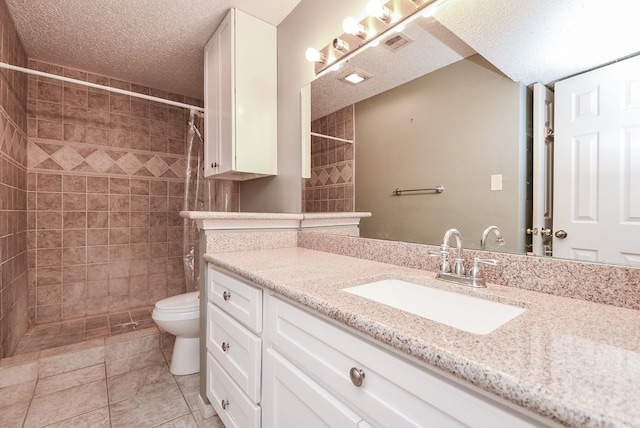 bathroom featuring vanity, tile patterned flooring, toilet, a textured ceiling, and a tile shower