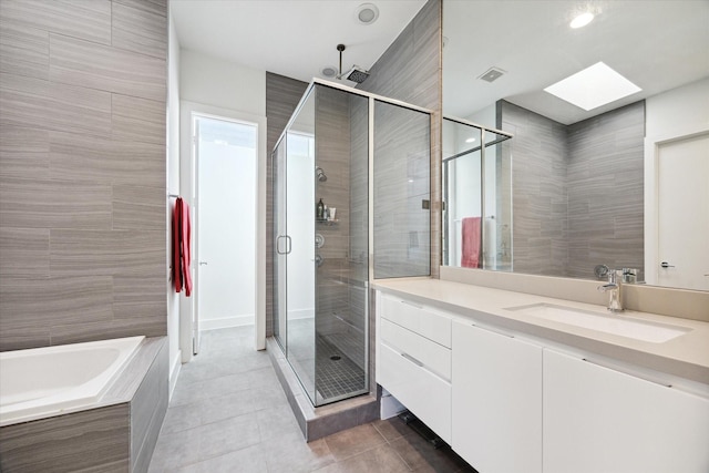 bathroom with tile patterned flooring, vanity, a skylight, and shower with separate bathtub