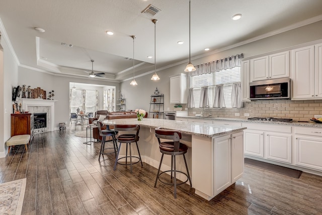 kitchen featuring a center island, white cabinets, a raised ceiling, sink, and stainless steel appliances