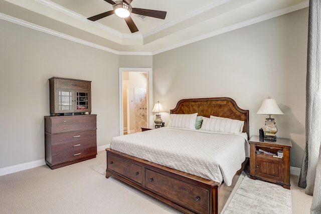 carpeted bedroom with a raised ceiling, connected bathroom, ceiling fan, and ornamental molding