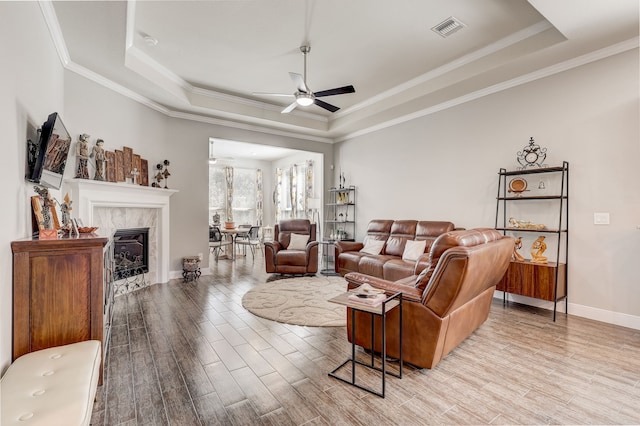 living room with a tray ceiling, ceiling fan, and ornamental molding