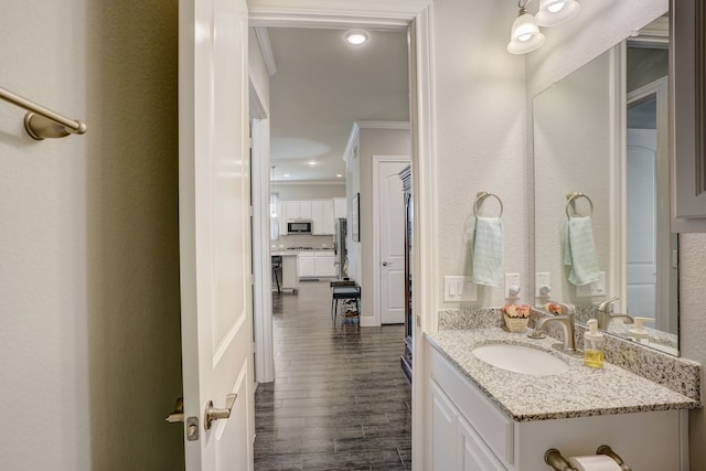 bathroom with hardwood / wood-style floors, vanity, ornamental molding, and tasteful backsplash