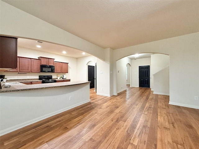 kitchen with black appliances, sink, vaulted ceiling, light hardwood / wood-style floors, and kitchen peninsula