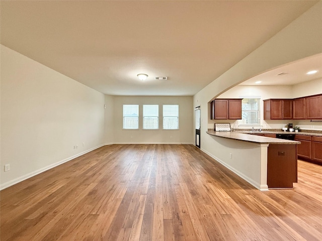 kitchen with a kitchen breakfast bar, kitchen peninsula, sink, and light hardwood / wood-style flooring