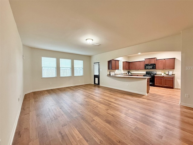 kitchen with light wood-type flooring, a kitchen breakfast bar, range with electric cooktop, and kitchen peninsula