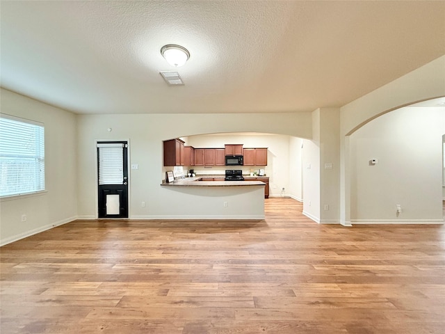 unfurnished living room with light hardwood / wood-style floors and a textured ceiling