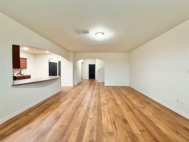 unfurnished living room featuring light wood-type flooring and a textured ceiling