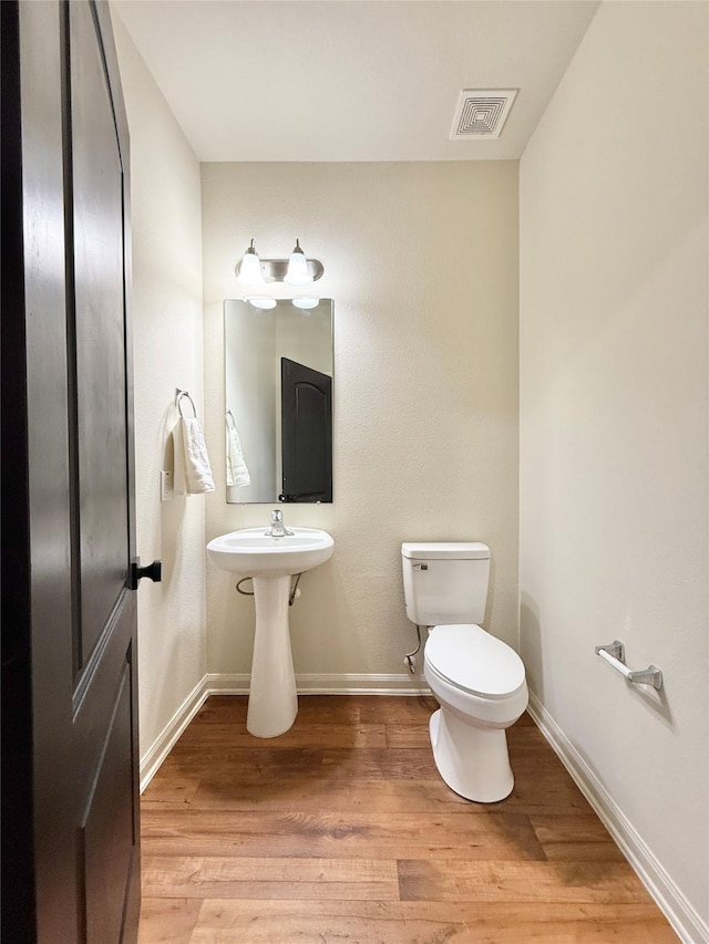 bathroom featuring toilet and wood-type flooring