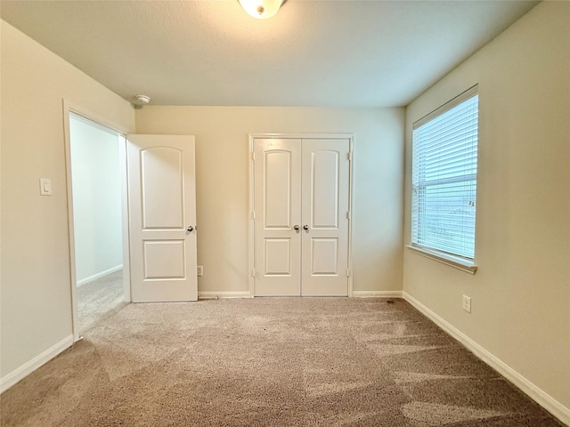 unfurnished bedroom with multiple windows, carpet, and a closet