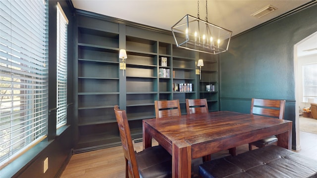 dining space featuring hardwood / wood-style floors, a notable chandelier, and ornamental molding