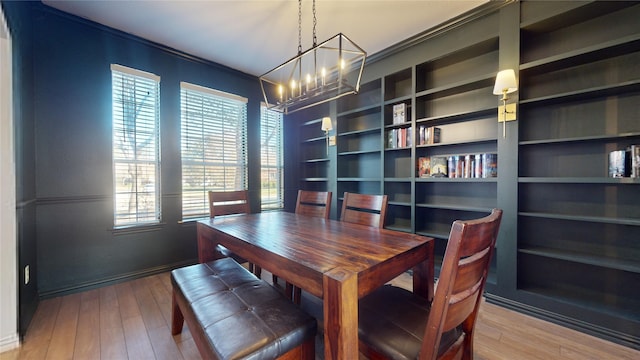 dining space with built in shelves, plenty of natural light, a notable chandelier, and hardwood / wood-style flooring