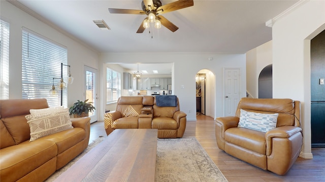 living room featuring crown molding, light hardwood / wood-style flooring, and ceiling fan with notable chandelier