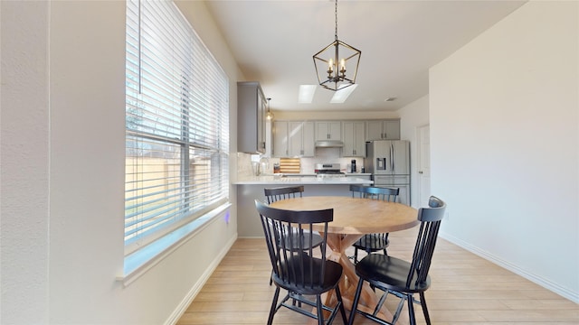 dining space featuring light hardwood / wood-style floors, sink, and a chandelier