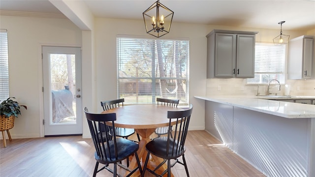 dining room featuring an inviting chandelier, ornamental molding, sink, and light hardwood / wood-style flooring