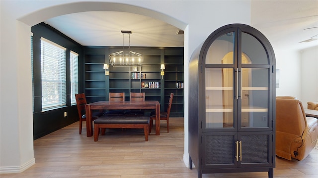 dining space with built in features, a notable chandelier, and hardwood / wood-style flooring