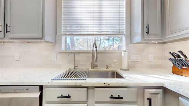 kitchen with light stone countertops, dishwasher, sink, backsplash, and gray cabinets