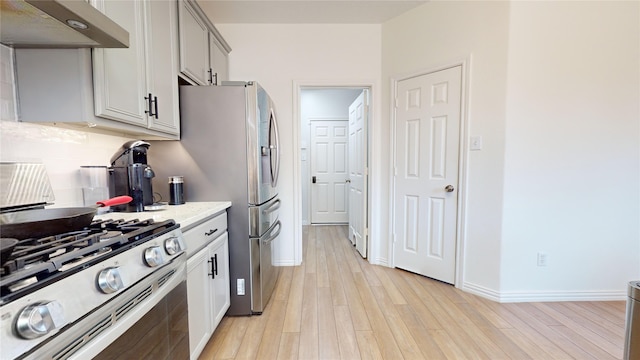 kitchen with light stone countertops, backsplash, stainless steel appliances, light hardwood / wood-style flooring, and range hood